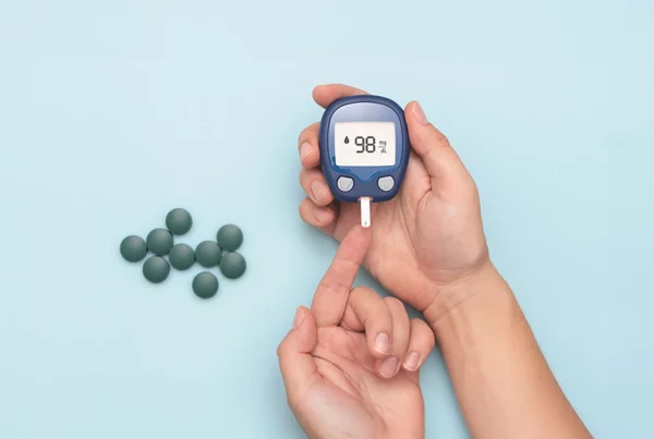 Glucometro con mano y espirulina en comprimidos